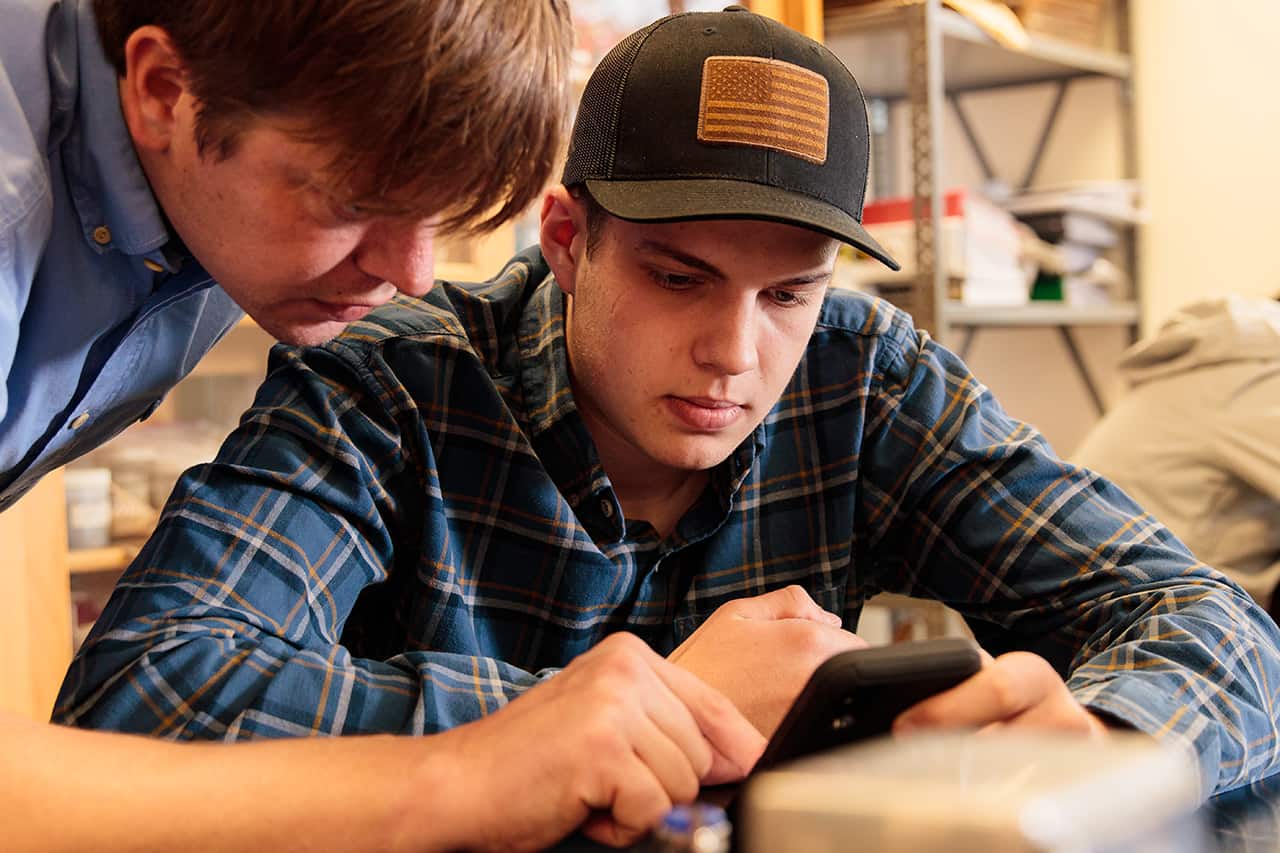 A UMFK professor assists a male student in class