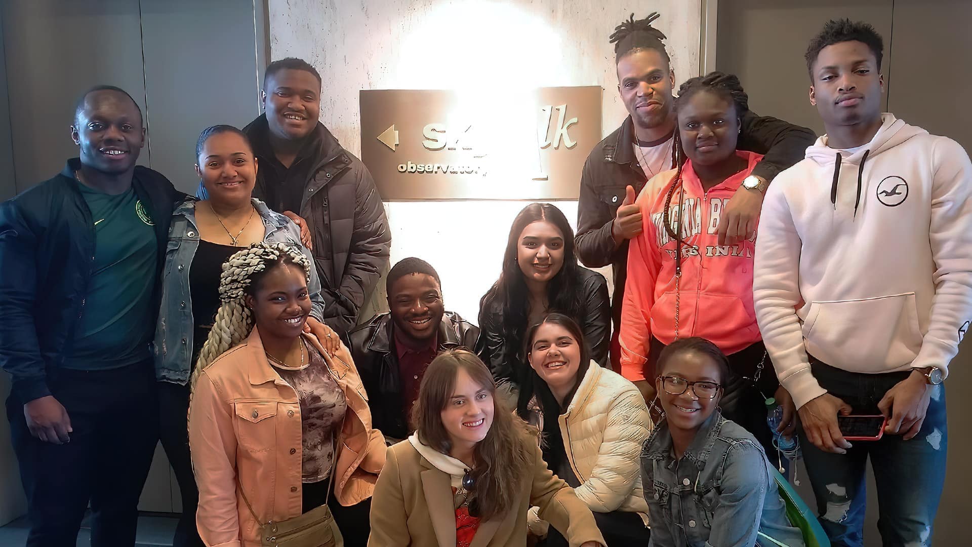 Students pose in a hotel hallway in front of elevators