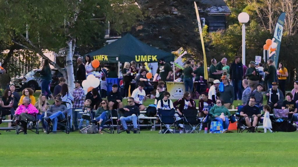 A crowd gathers along the sidelines of Michael Simon Field to watch a homecoming soccer game.