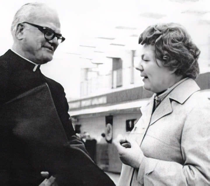 Marcella conversing with a Catholic priest