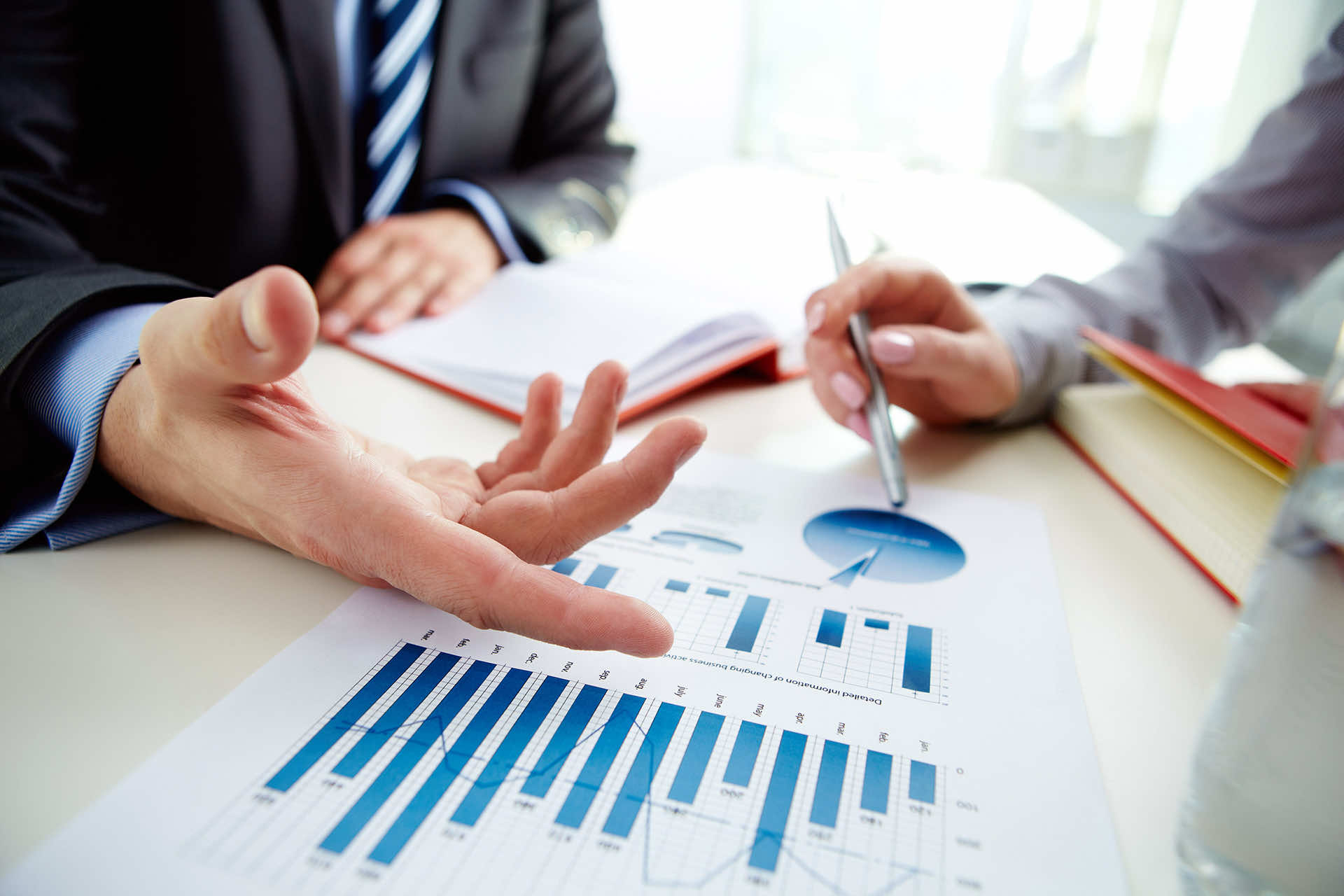 a supervisor and employee sit at a table reviewing a report with charts